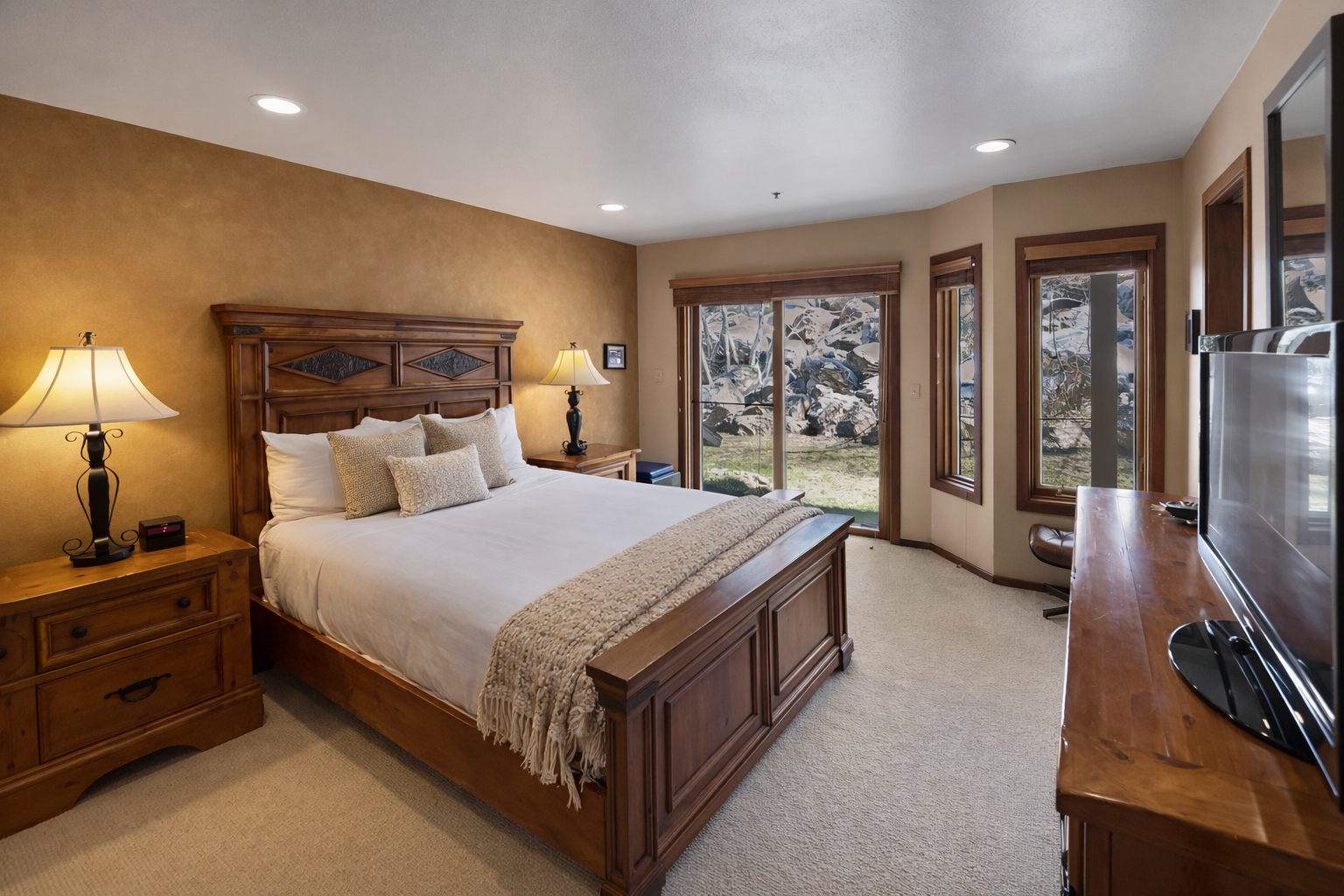 Drift off peacefully in your cozy bedroom overlooking a serene natural landscape through expansive windows.
