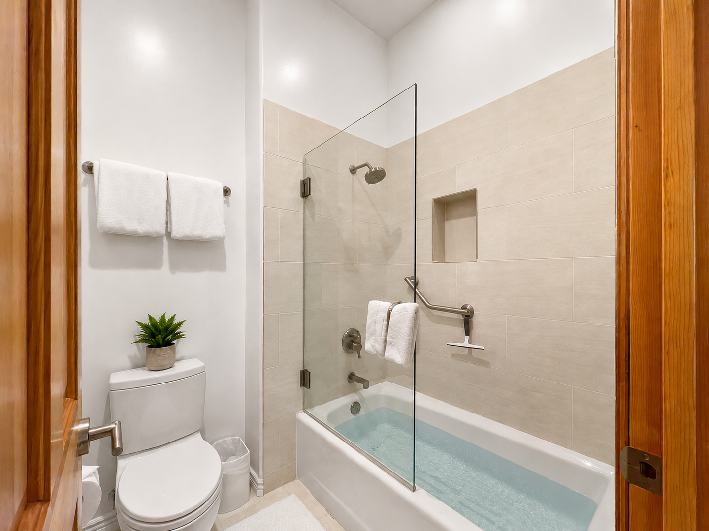 Relax in your spotless private bathroom with sleek modern finishes, a glass-enclosed tub-shower combo, and plush towels waiting for you.