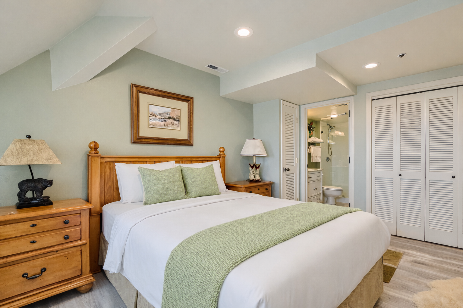 Sink into comfort in your serene bedroom with soft green accents, natural wood furnishings, and your own private bathroom sanctuary.