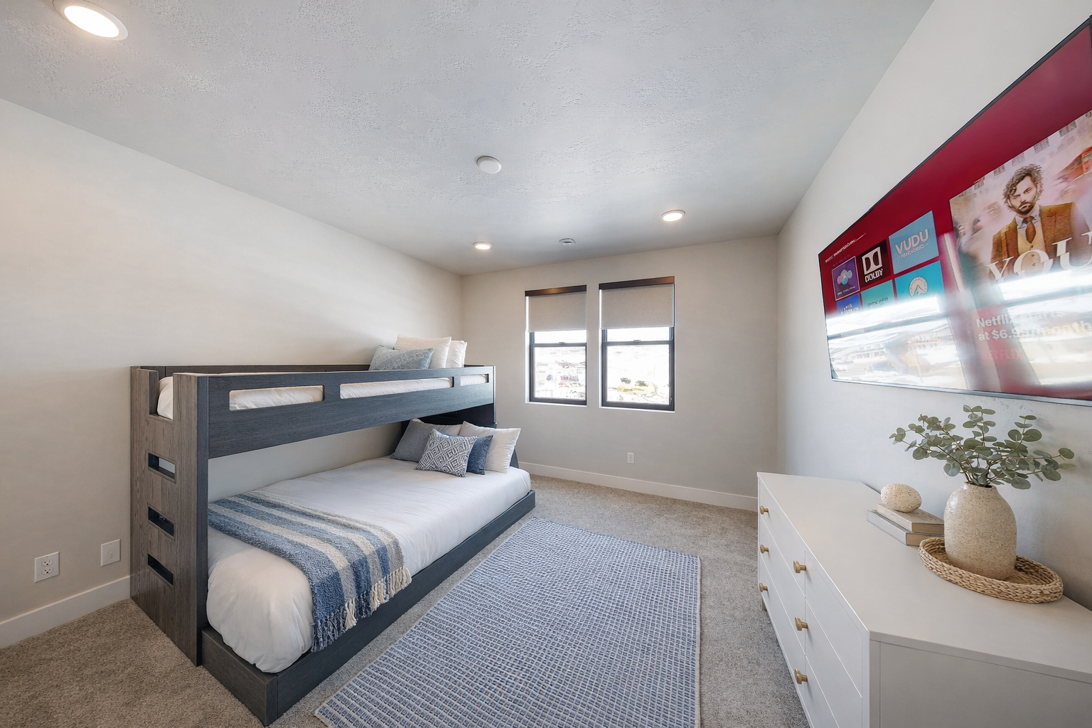 Perfect for kids or groups, this modern bunk room features sleek gray beds and a cozy blue gingham rug. Large windows offer bright, natural light and peaceful mountain views.