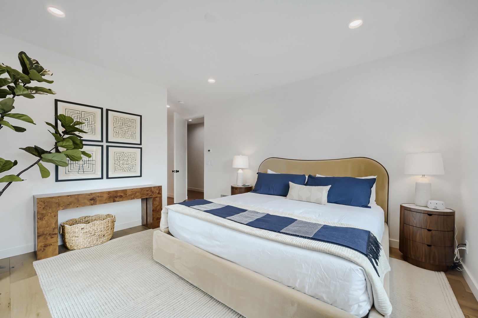 Sink into crisp white linens and plush pillows in your serene bedroom, where warm wood tones and thoughtful touches create the perfect retreat for a restful night.