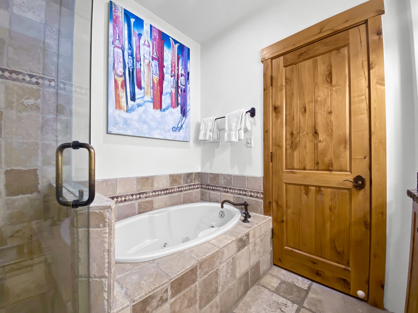 Unwind in this charming bathroom featuring a spacious jetted tub and elegant tile surround. The warm, knotty wood door adds a cozy, rustic touch to your relaxing retreat.