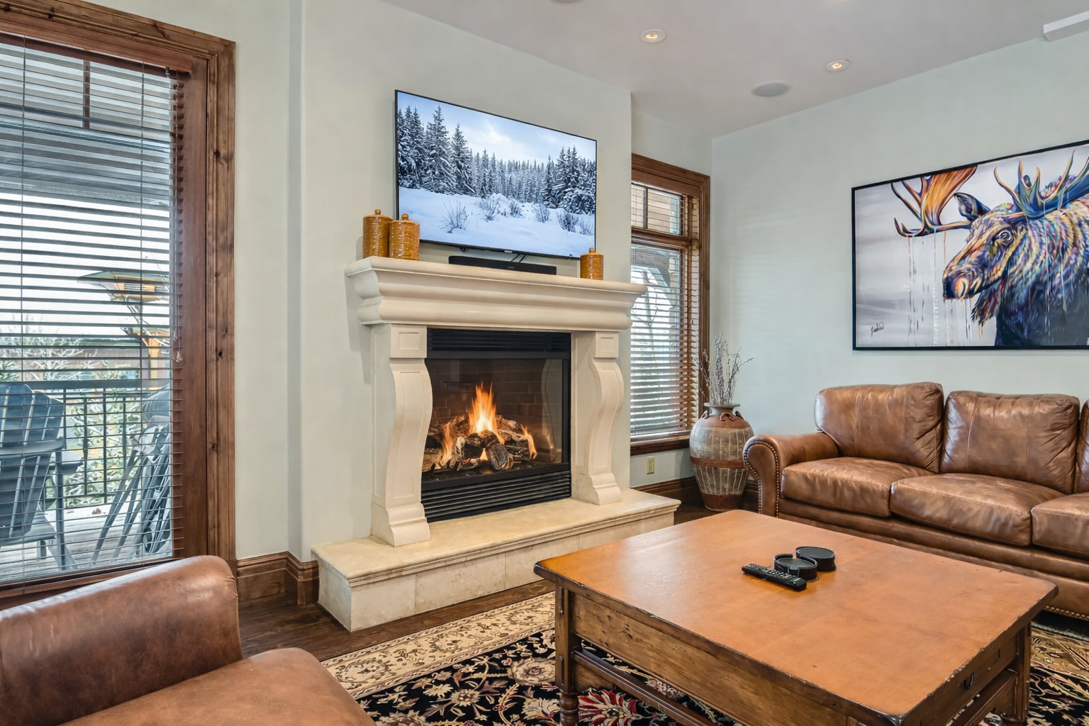 Relax in this bright, open-concept living area at Strand Haus, featuring plush leather seating, a cozy gas fireplace, and a large smart TV.