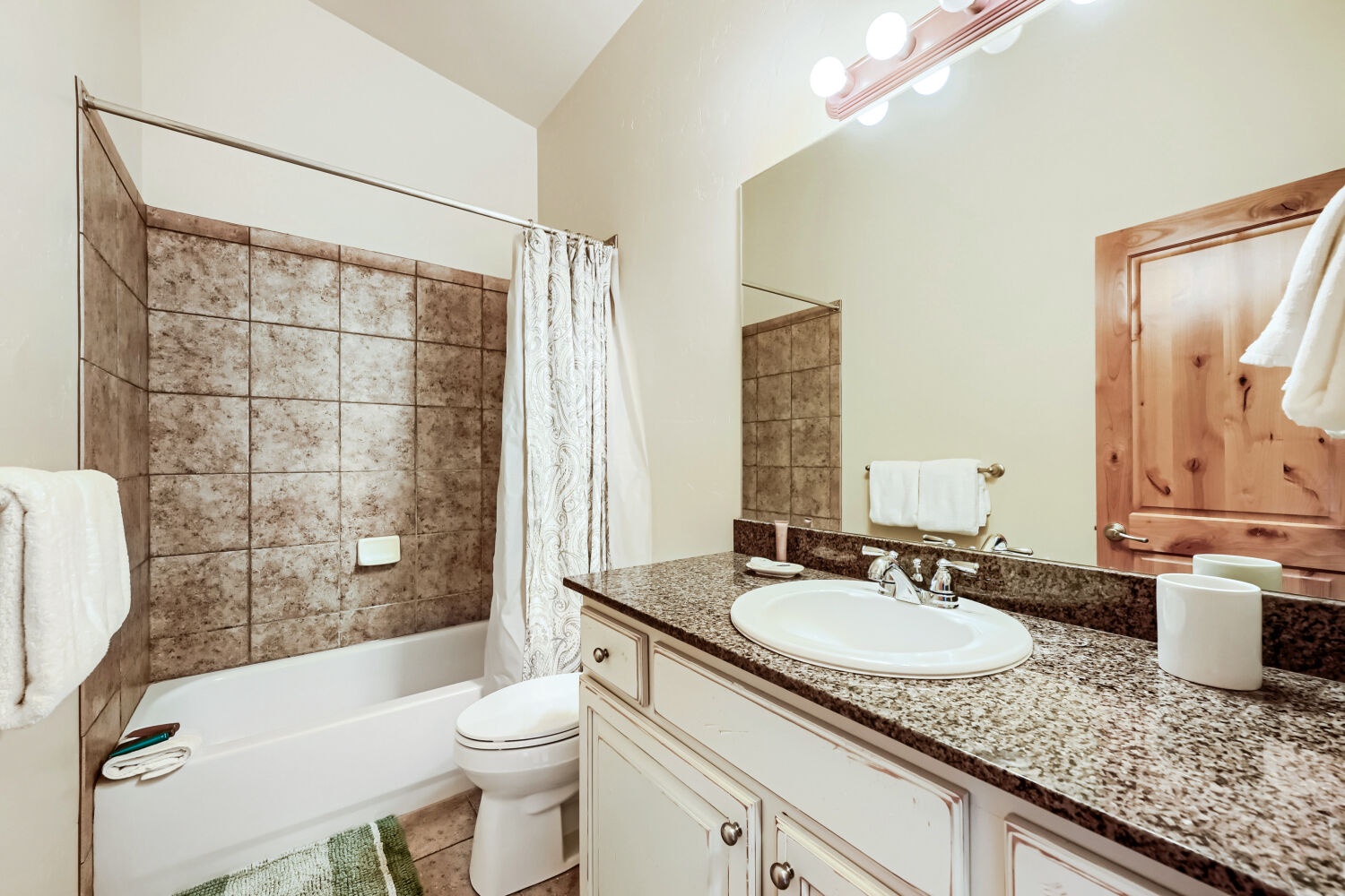 Your private bathroom features a soaking tub, granite countertops, and warm wood accents—perfect for unwinding after a day exploring the area.
