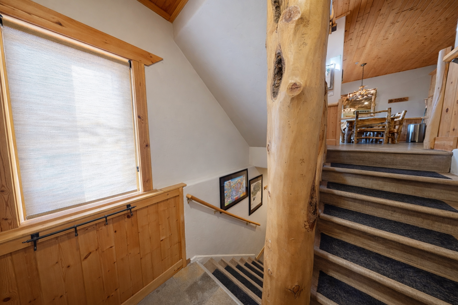 Rustic wooden staircase connects your levels with charming log beam detail and natural light streaming through the window.