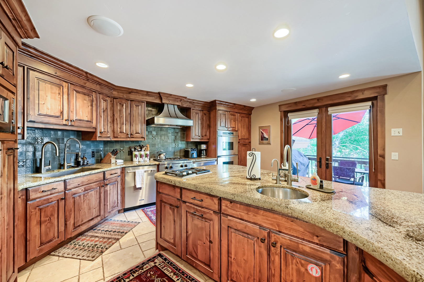 Gather around gleaming granite counters and rich wood cabinetry in your spacious kitchen. Natural light pours through the door leading to your private outdoor space, perfect for morning coffee or evening meals al fresco.