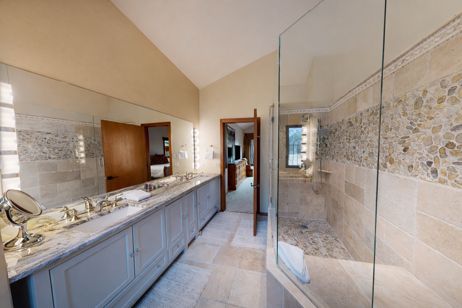 Unwind in your luxurious spa-like bathroom with dual vanities, granite counters, and a glass-enclosed stone shower.