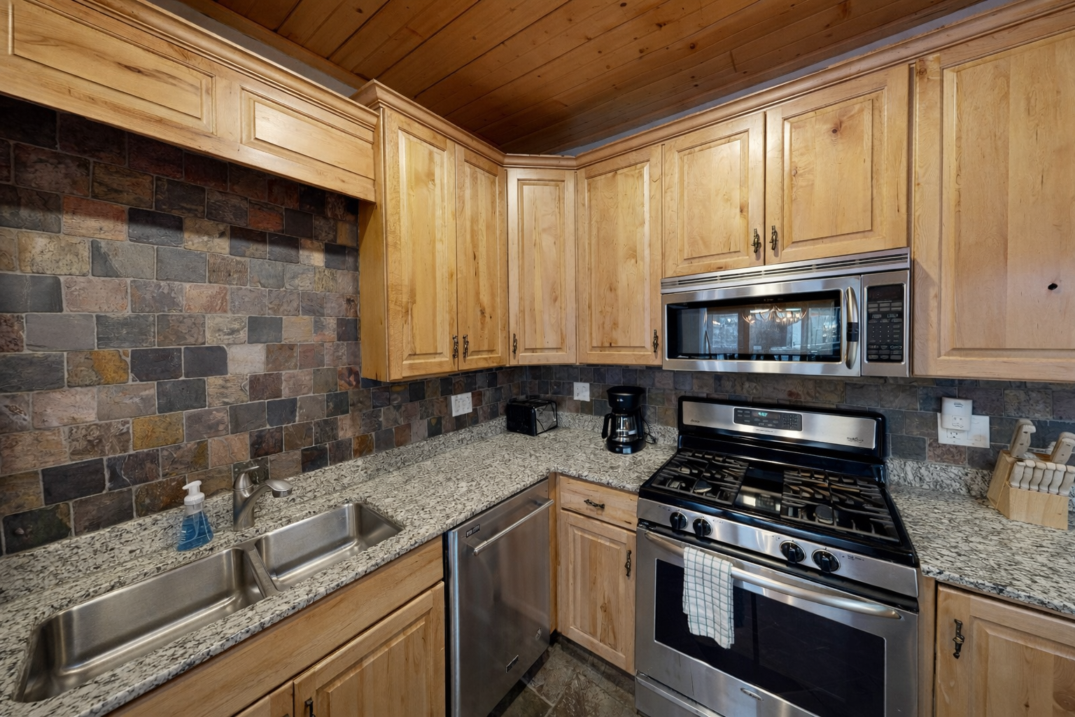 Step into your rustic-modern kitchen where natural wood cabinets and stone backsplash create the perfect mountain cooking sanctuary.