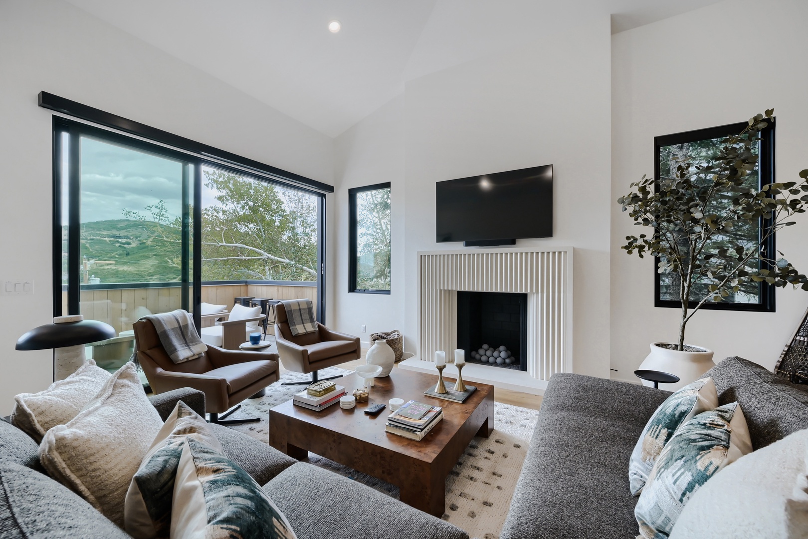 Sink into plush seating by the fireplace as natural light floods through floor-to-ceiling windows, framing mountain views that invite you to unwind in style.