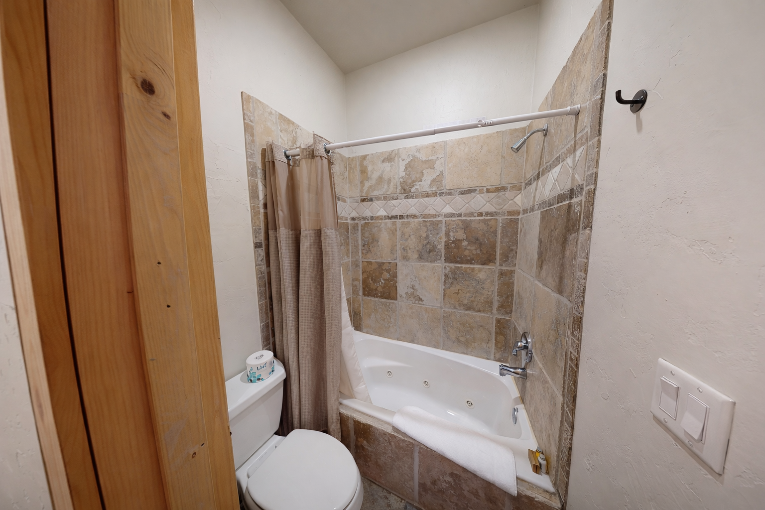 Unwind in your private bathroom featuring a jetted tub, elegant tile work, and a soothing shower—perfect for relaxing after a day of adventure.