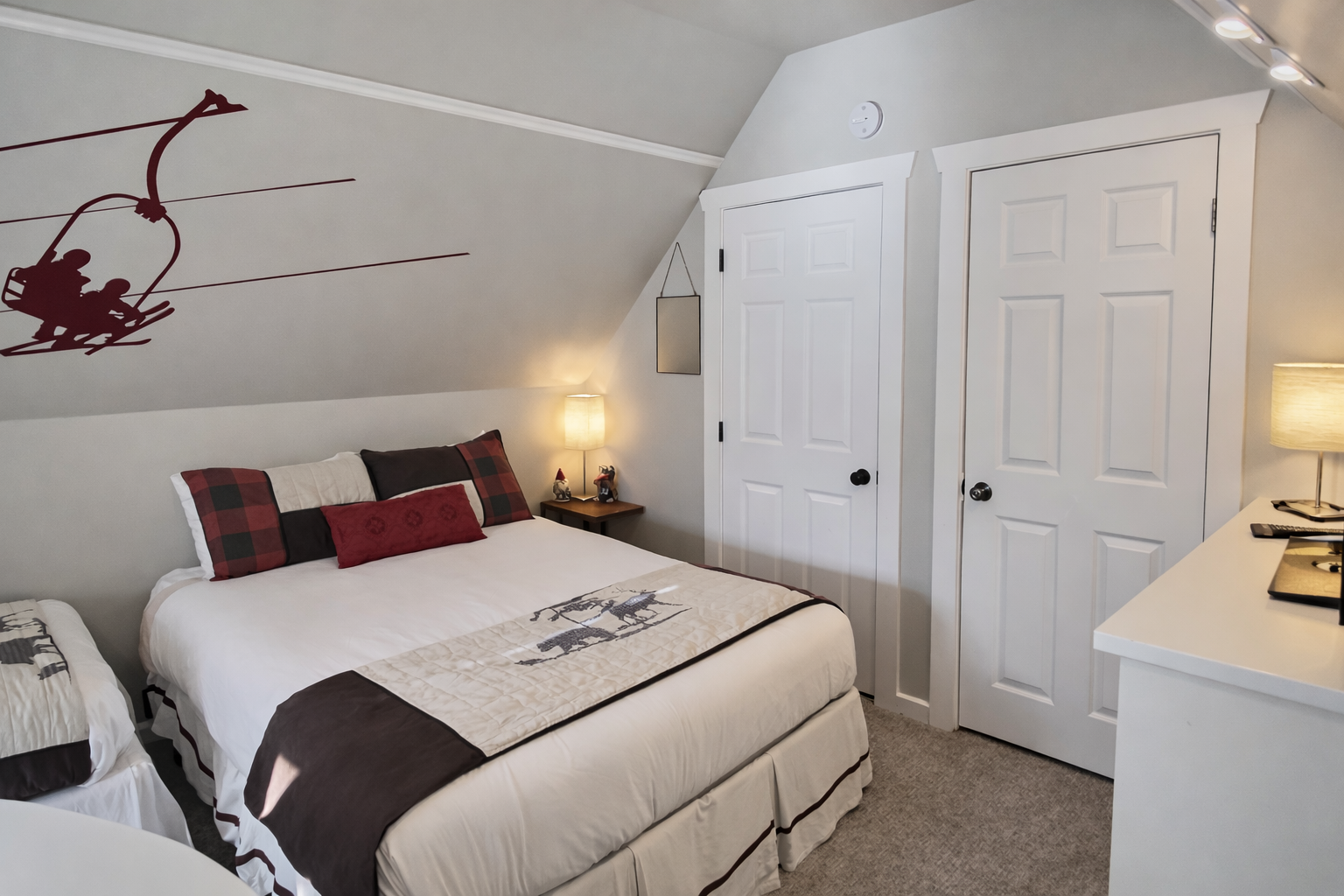 Unwind in the cozy attic bedroom, featuring a large smart TV, dedicated storage, and a comfortable bed under charming sloped ceilings.