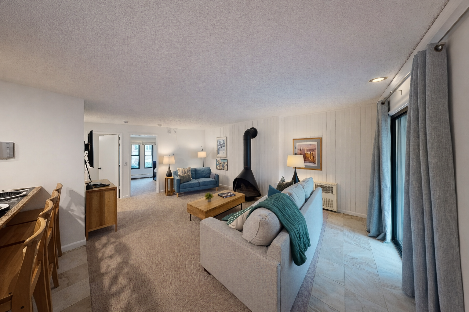 Unwind in your spacious living area with cozy seating, striking fireplace, and abundant natural light streaming through large windows.