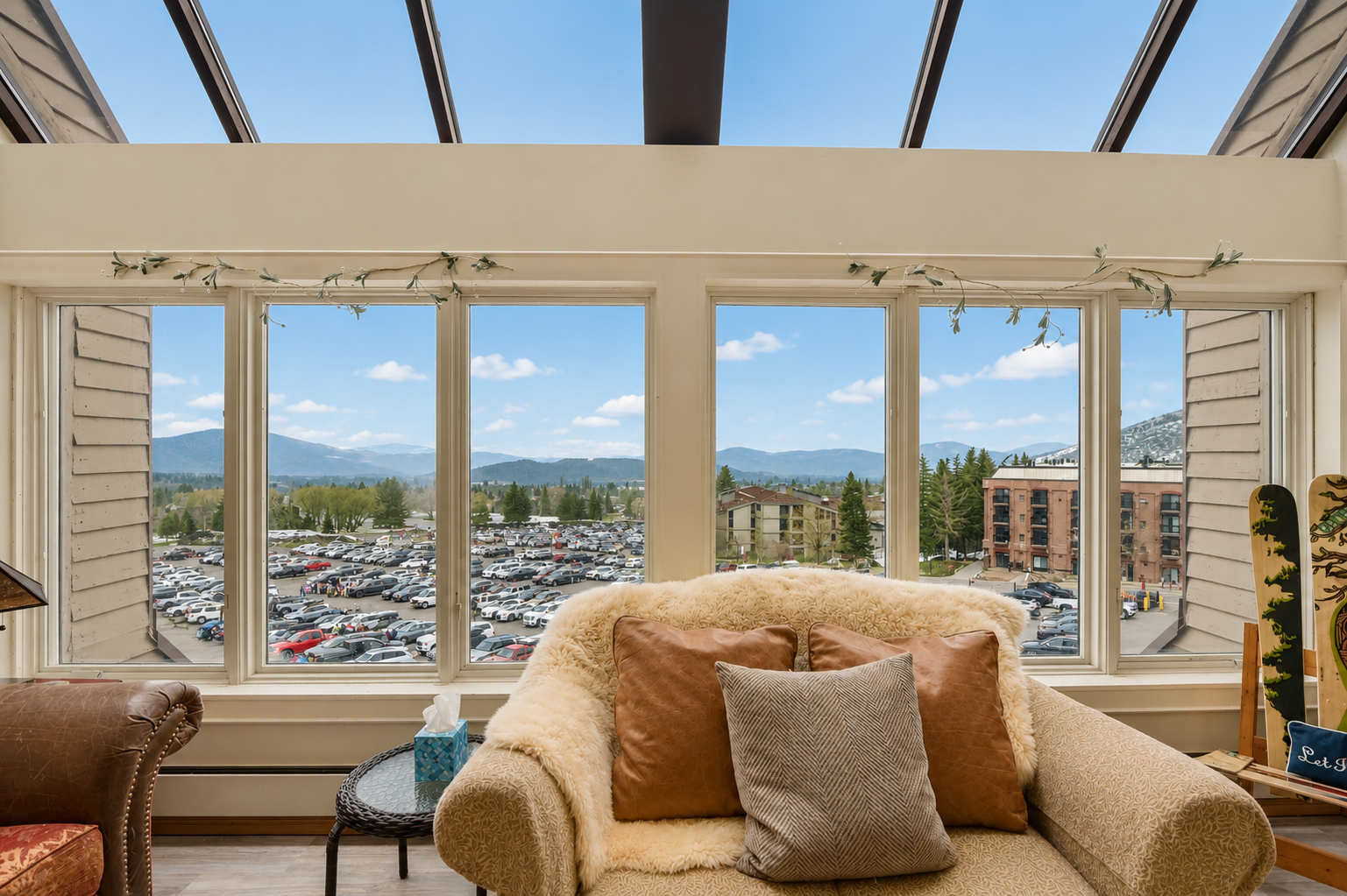 Sink into plush seating and let your eyes wander across mountain vistas through floor-to-ceiling windows, where natural light floods your peaceful retreat under a skylight canopy.