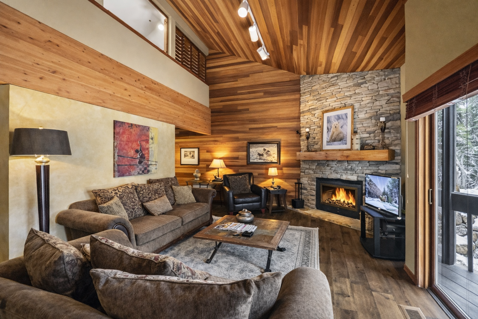 Sink into plush sofas by your crackling fireplace, where warm wood tones and mountain views create the perfect retreat.