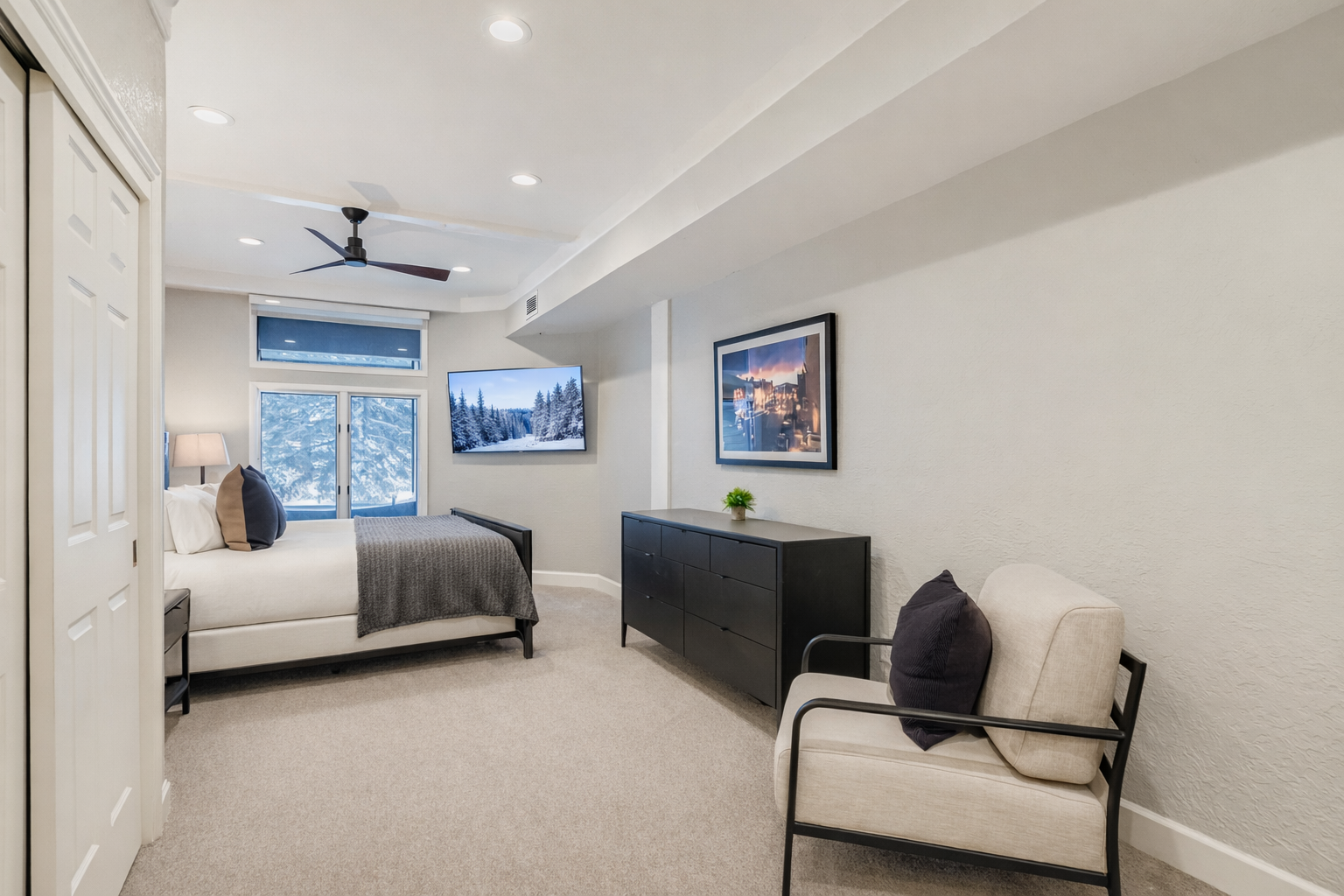 Rest peacefully in your elegant bedroom with comfortable bedding, mountain views, and modern amenities including a ceiling fan and wall-mounted TV.