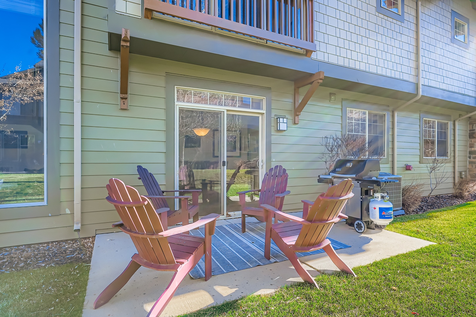 Your private patio awaits with Adirondack chairs, a grill, and a grassy backyard—perfect for morning coffee or evening barbecues under the open sky.