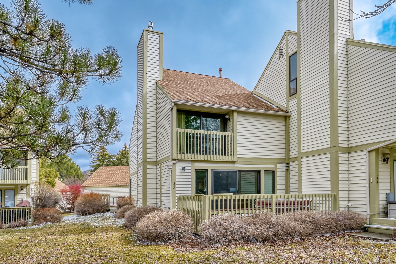 Modern townhome featuring multiple levels with private balconies, nestled among mature trees in a peaceful residential setting.