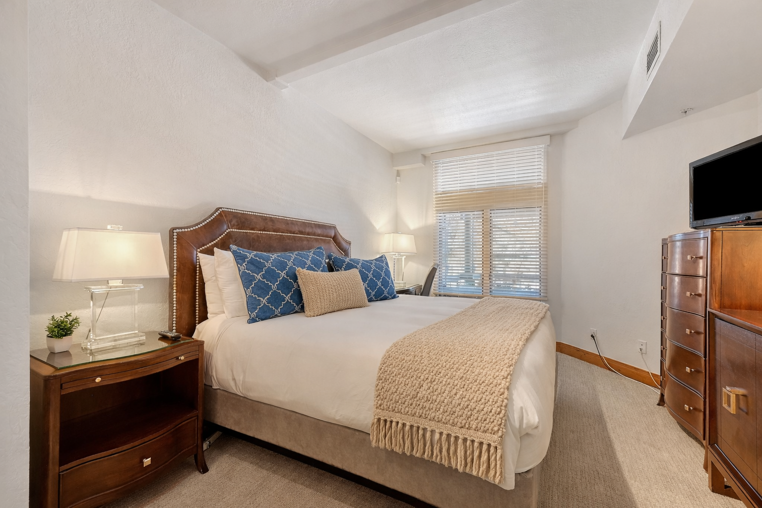 Relax in this peaceful bedroom retreat featuring a plush king bed, stylish decor, and warm lighting. A tranquil oasis for your stay.