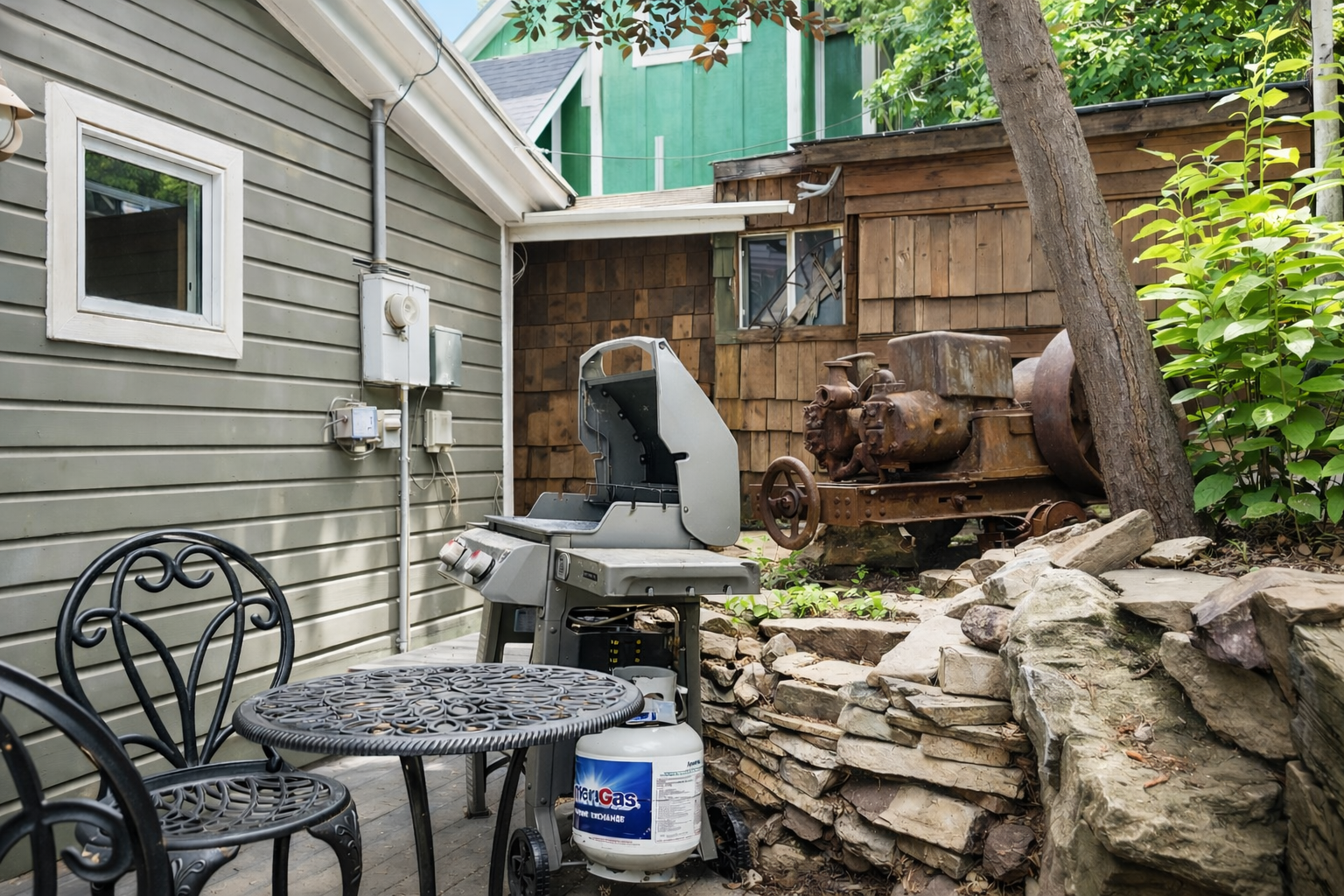 Your private patio features a gas grill and charming seating, perfect for outdoor meals surrounded by lush greenery and rustic charm.