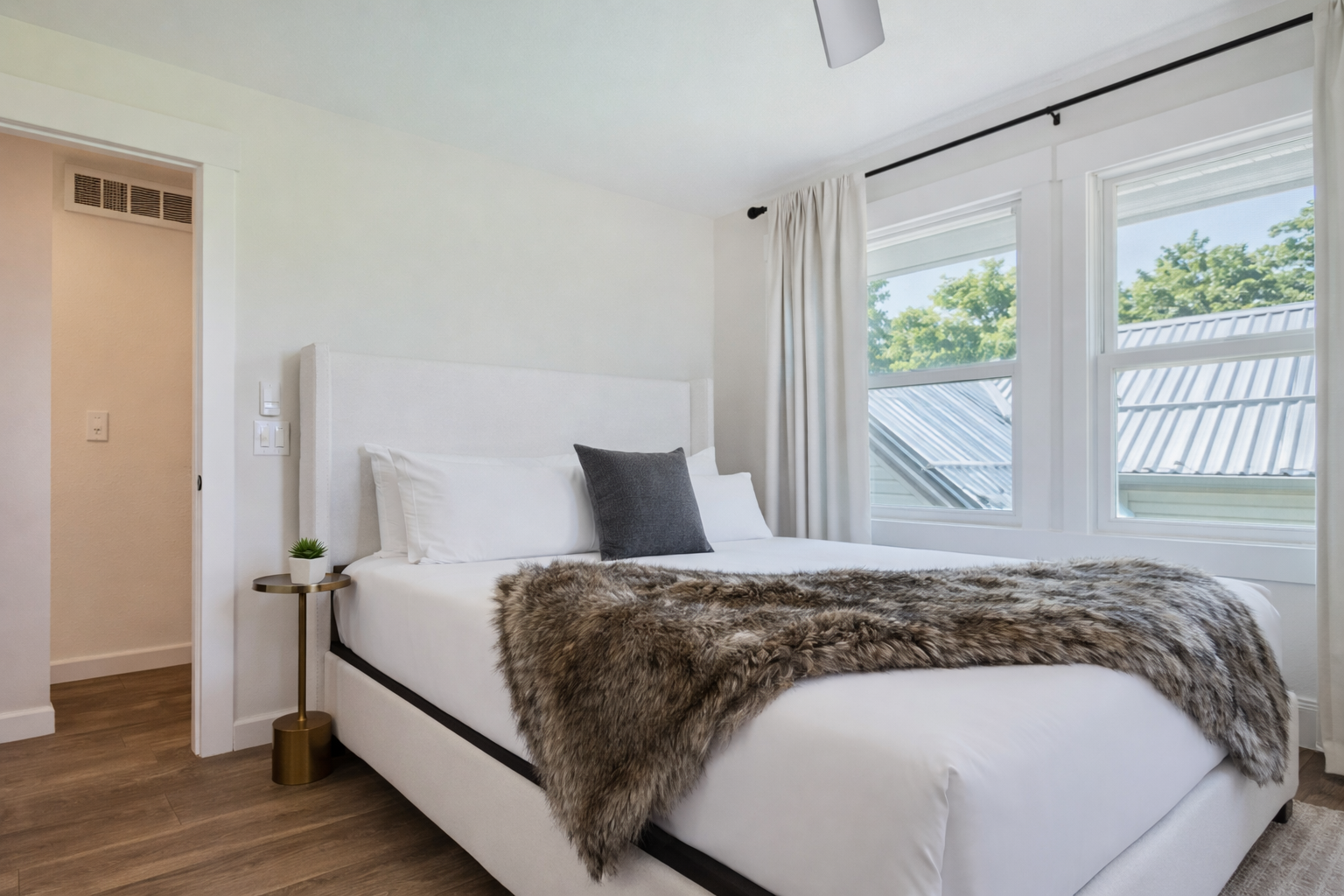 Sink into crisp white linens and cozy faux fur throws in your serene bedroom retreat, where natural light streams through large windows.