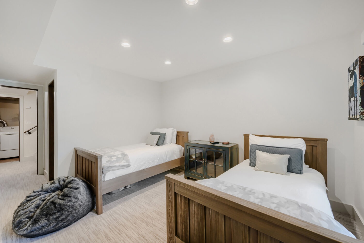 Two comfortable twin beds welcome you to a serene, light-filled space with warm wood tones and soft linens. Your peaceful retreat awaits.
