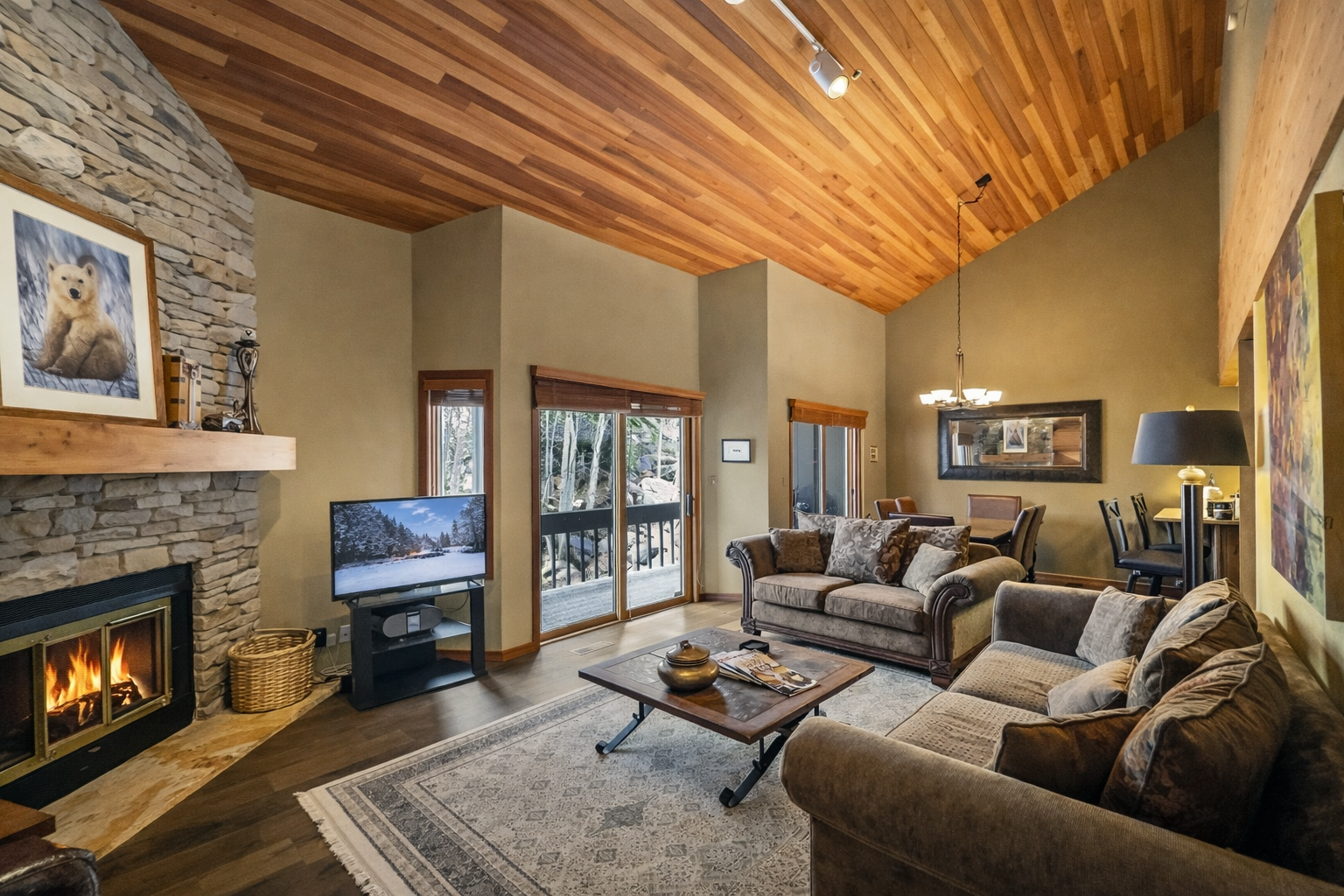 Unwind in your cozy living space with stone fireplace warmth and mountain views through sliding doors.