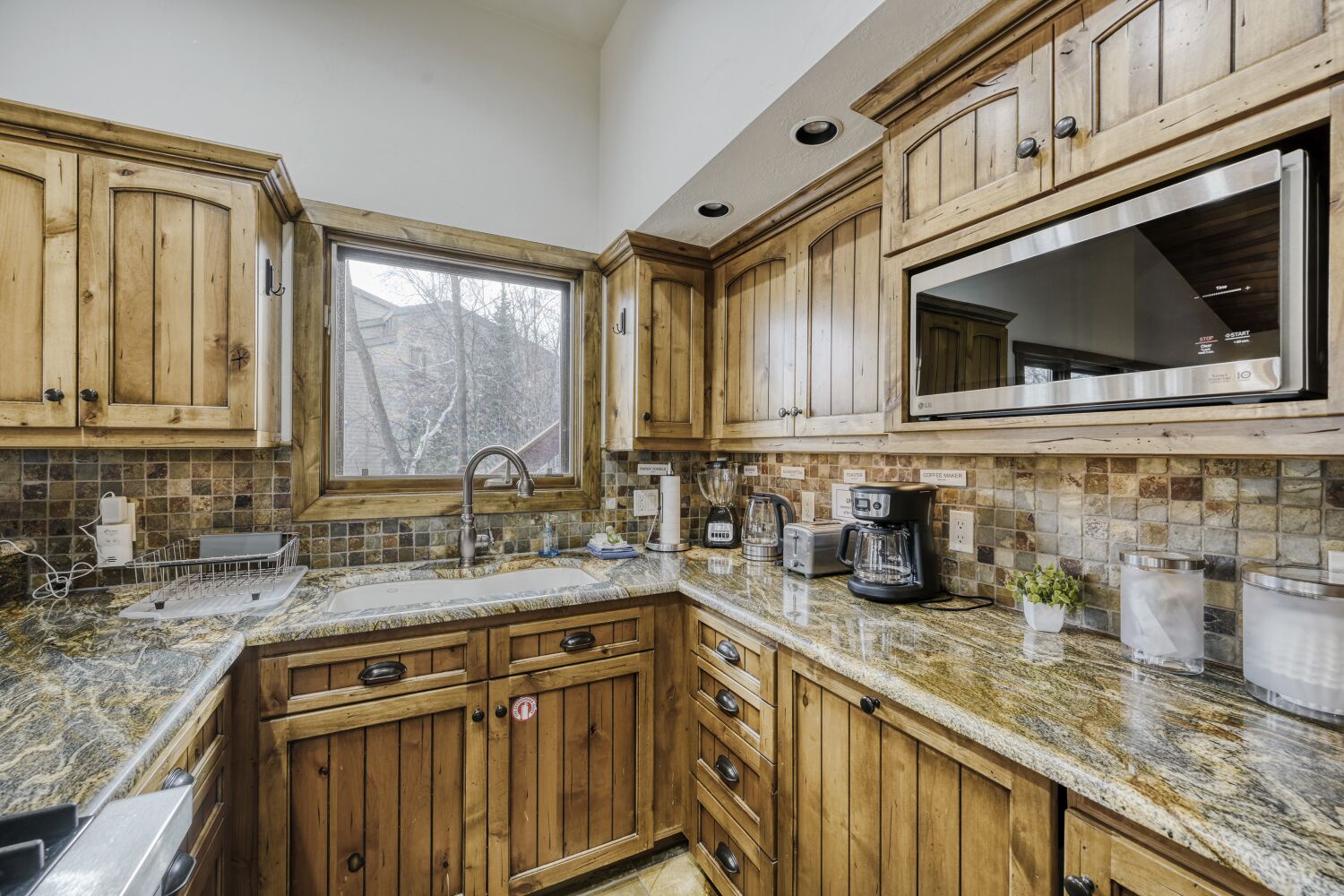 Prepare delicious meals in this fully equipped kitchen featuring rustic wood cabinets, granite countertops, and modern appliances for your culinary adventures.