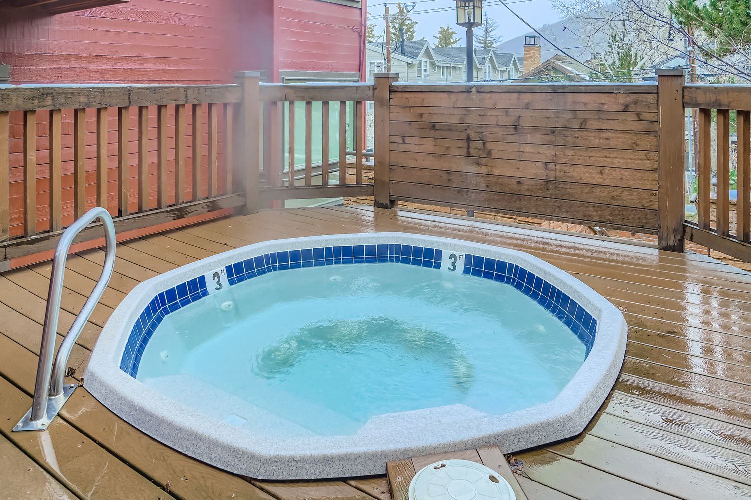 Unwind in your private hot tub on the wooden deck, surrounded by privacy fencing with views of the charming neighborhood beyond.