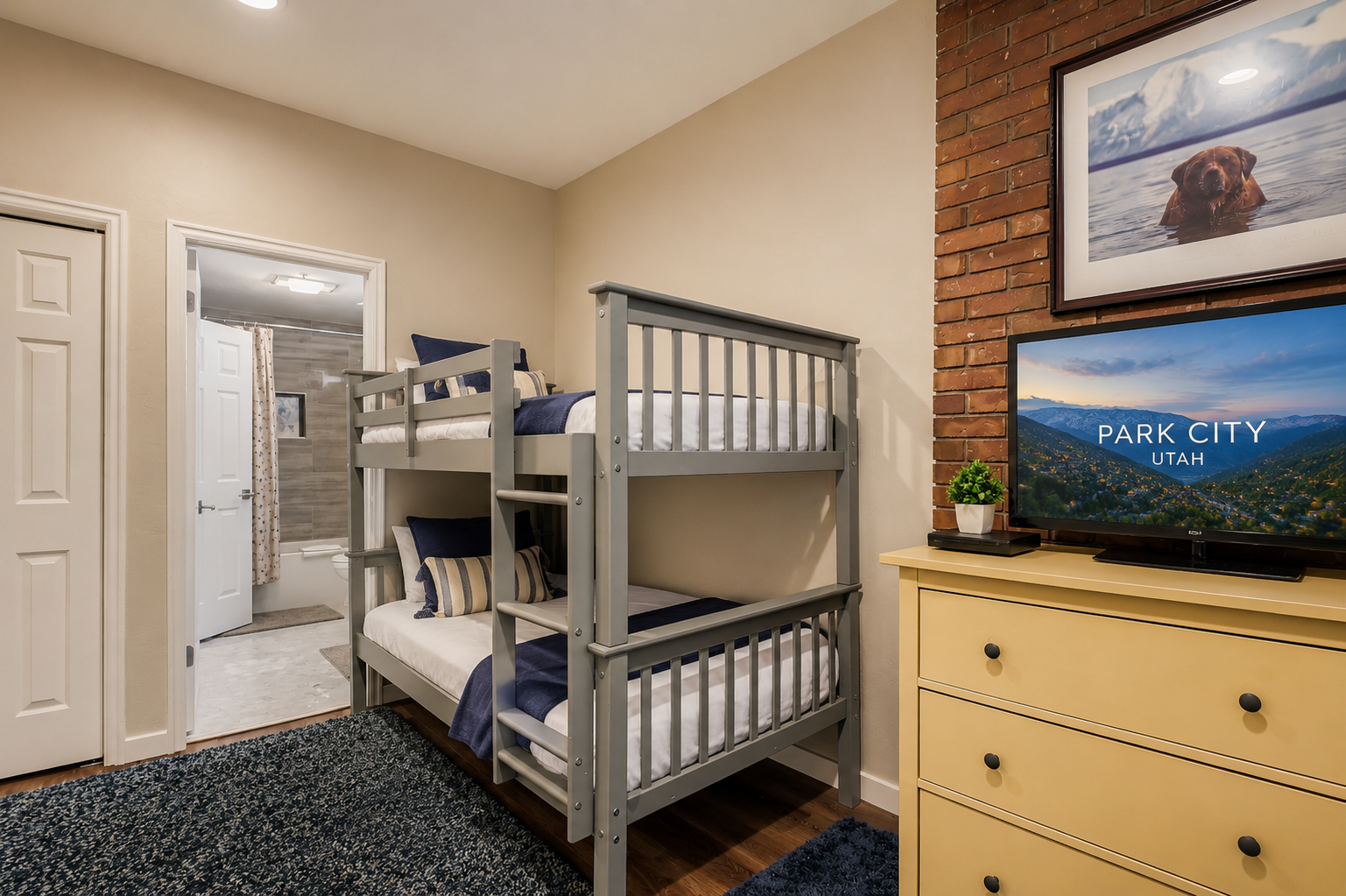 Your kids will love bunking here, with comfy twin beds, a large TV with scenic views, and a rustic exposed brick accent wall adding warmth to this cozy mountain retreat.