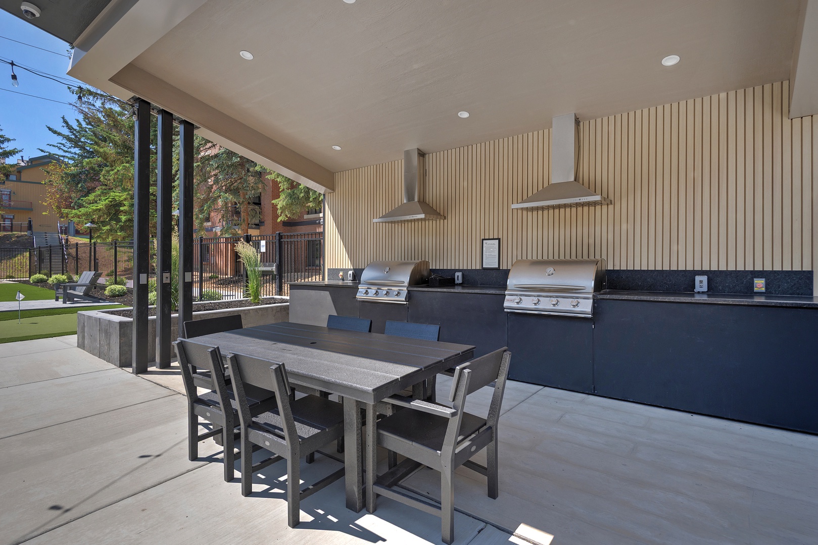 Gather around the communal outdoor dining table, where sleek grills await your culinary creations under the modern covered pavilion. This inviting BBQ area blends style and function for memorable meals.