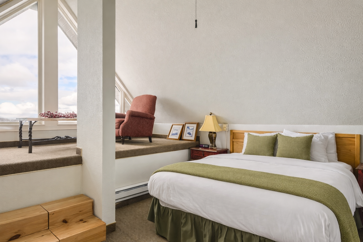 Cozy loft bedroom with a comfortable bed, ceiling fan, and unique sitting area. A tranquil mountain retreat for a restful stay in Park City.