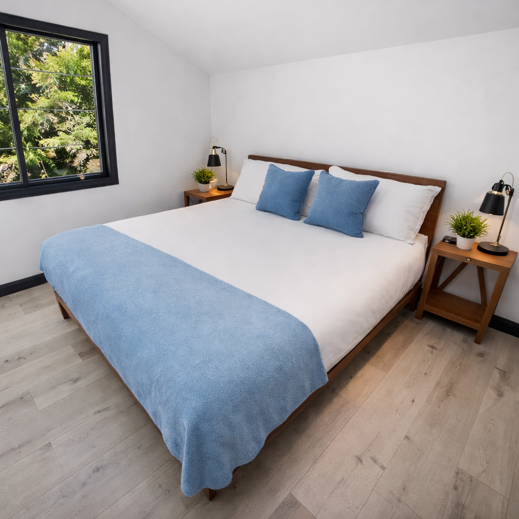 Drift into peaceful slumber in your serene bedroom, where soft blue linens meet warm wood tones and garden views create the perfect retreat.