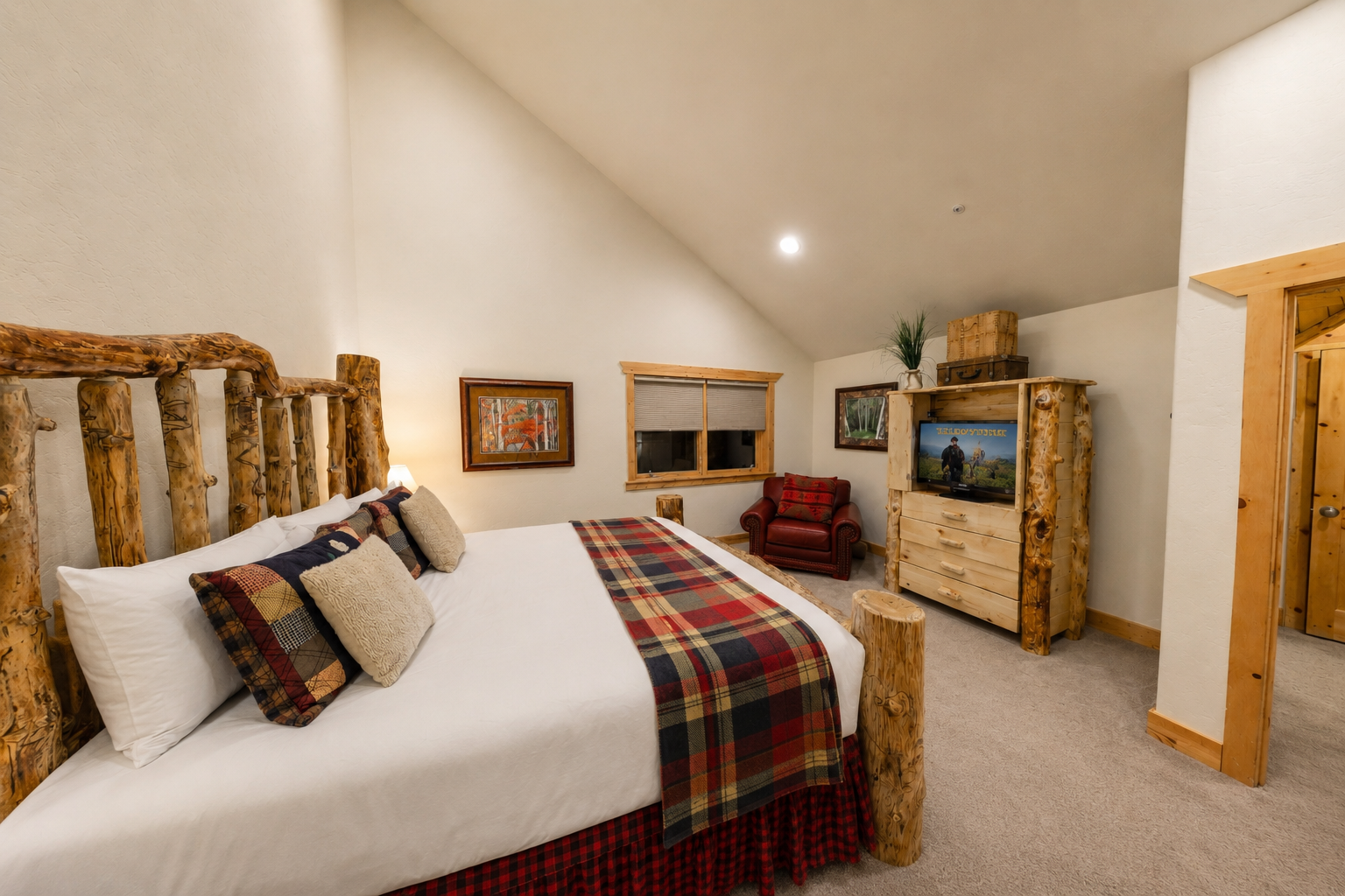 Unwind in your cozy bedroom with a handcrafted log bed, warm plaid accents, and rustic charm. Vaulted ceilings, a comfy armchair, and TV make relaxation effortless.