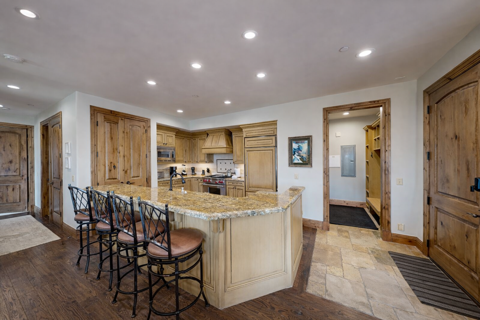 Prepare gourmet meals in this elegant, traditional kitchen. Featuring light wood cabinetry, a grand range hood, and a sprawling granite island, it's a chef's dream with high-end appliances.