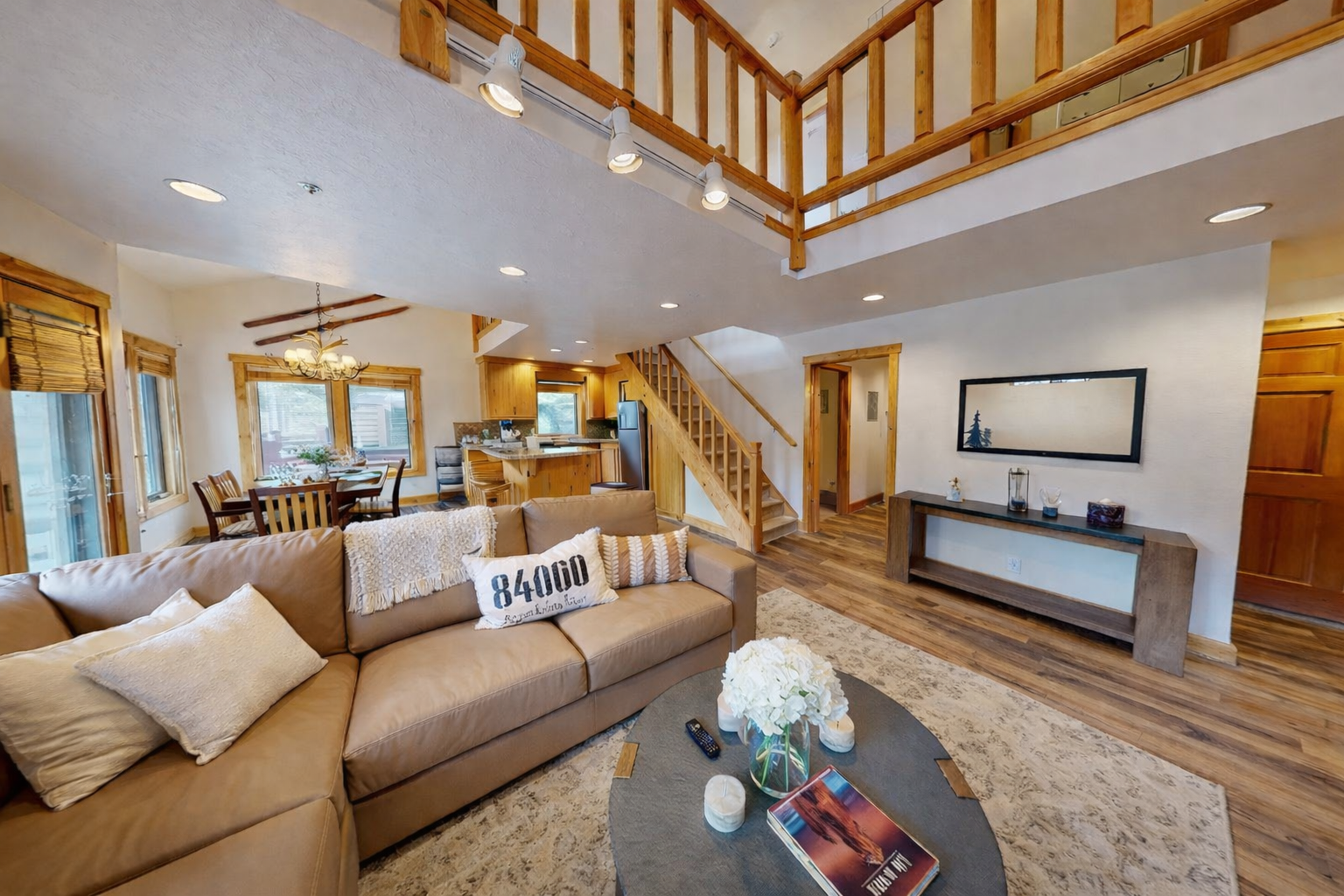 Relax in your spacious open-concept living area featuring soaring ceilings, warm wood details, and a loft-style layout that flows seamlessly into the kitchen.