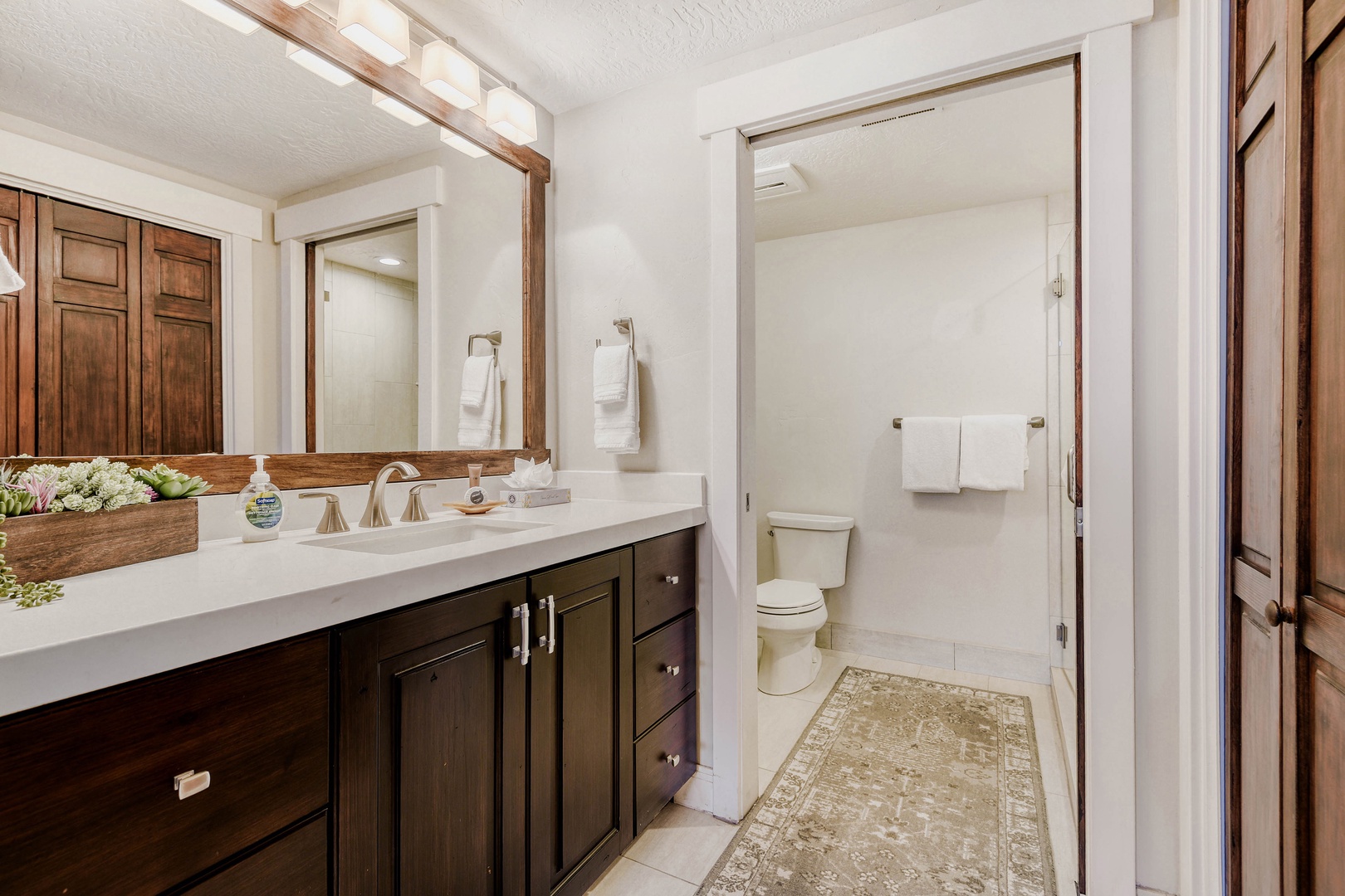 Your spacious bathroom features rich wood cabinetry, dual vanities, and pristine white countertops for a luxurious morning routine.