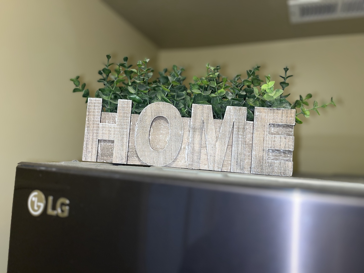 Make yourself at home! This charming "HOME" greenery accent adds a warm, welcoming touch to the modern kitchen, beautifully complementing the sleek stainless steel appliances.