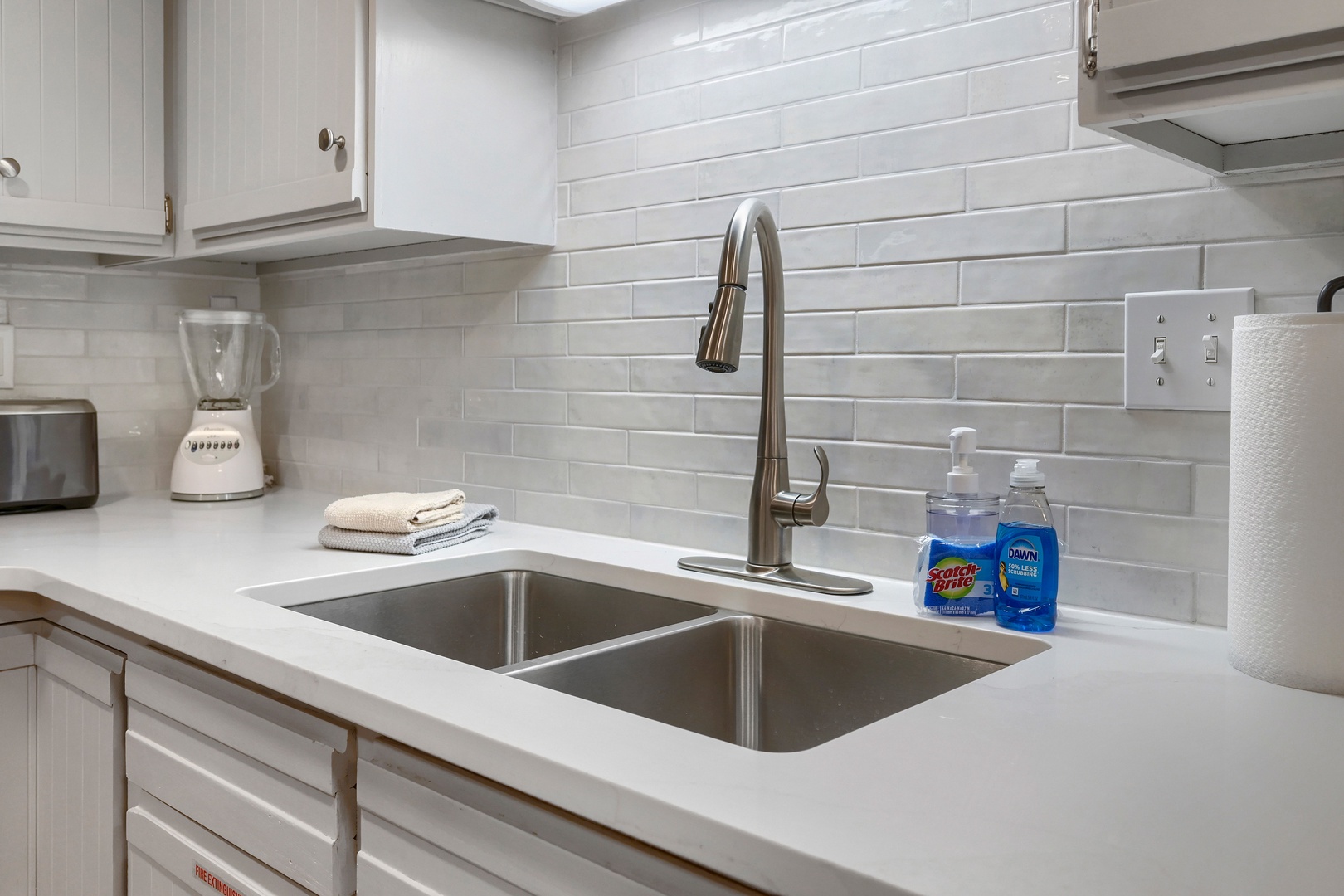 Clean, bright kitchen with sleek subway tile backsplash and stainless steel sink—perfect for preparing your favorite meals during your stay.