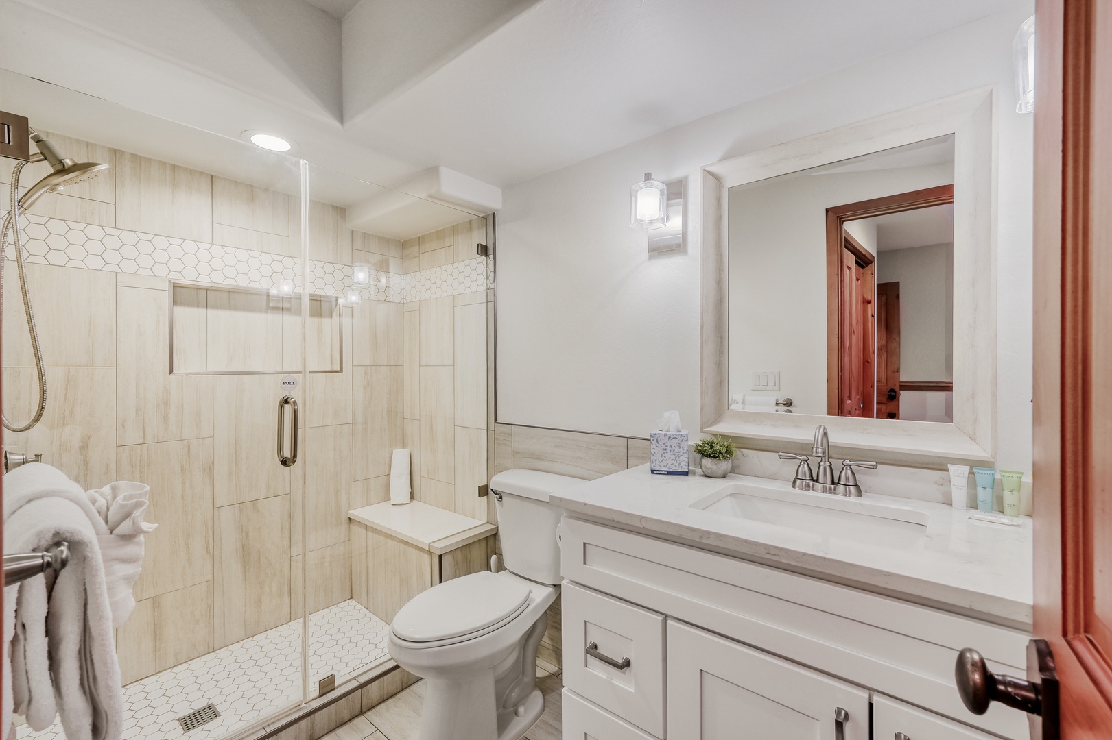 Your private bathroom features a glass-enclosed shower, white vanity, and modern fixtures for your comfort and convenience.