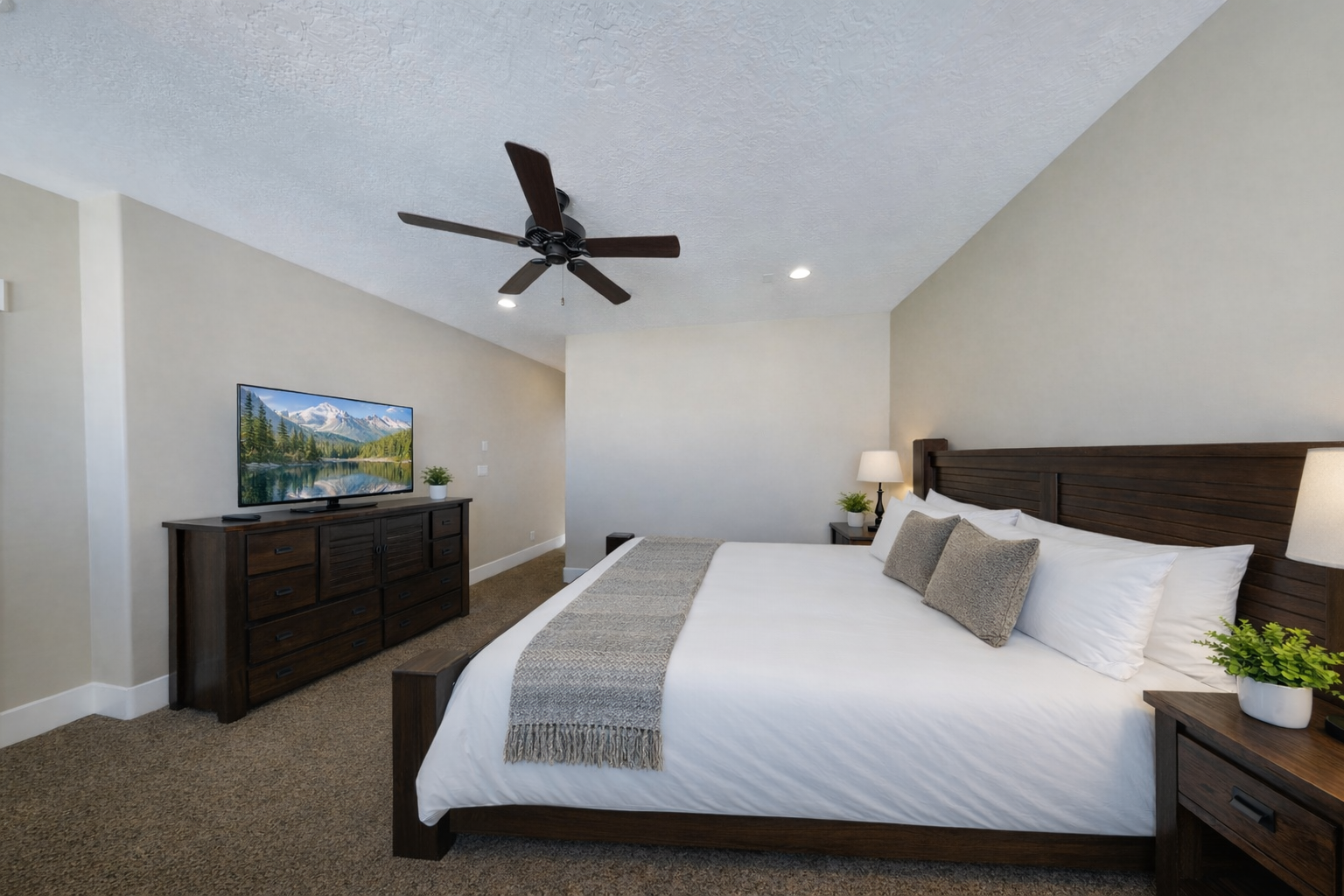 Relax in your spacious bedroom with plush bedding, entertainment center, and ceiling fan for perfect climate control comfort.