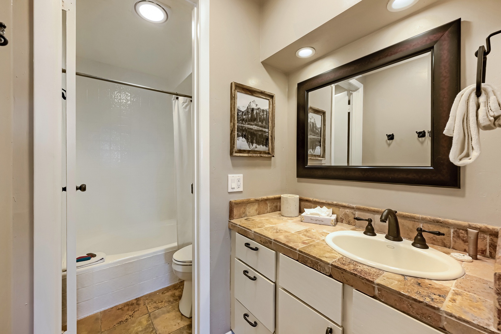 Your private bathroom features a spacious walk-in shower, framed mirror above a stone countertop, and cozy towels waiting for you after a refreshing rinse.
