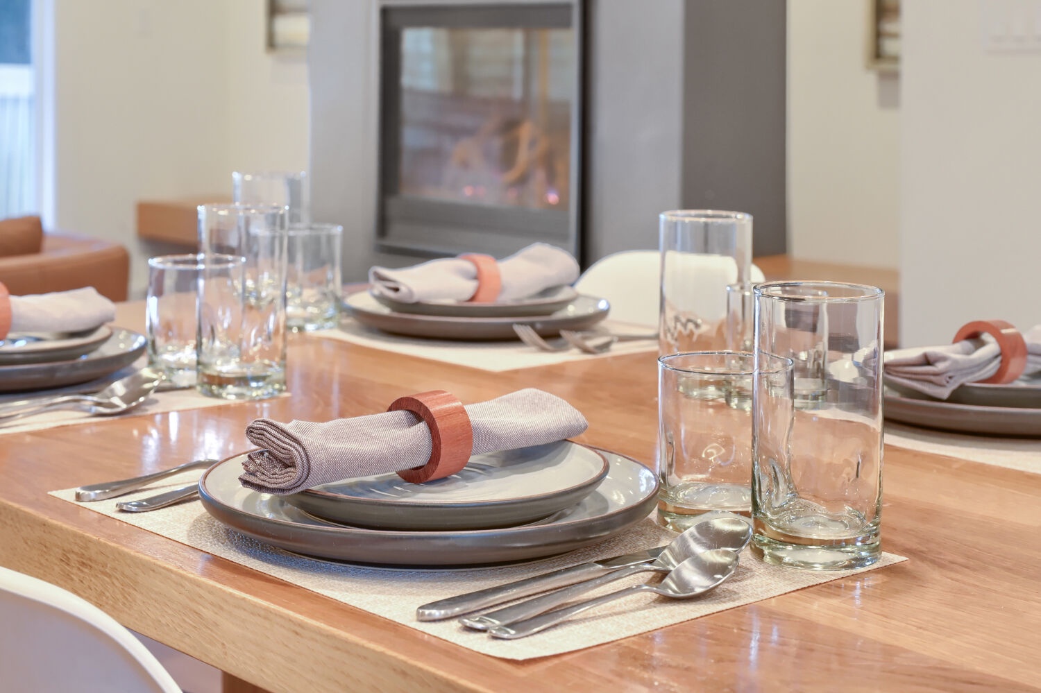 Gather around this elegantly set dining table, ready for your next meal. Stylish place settings and glassware await, creating a warm and inviting space for memorable dinners.