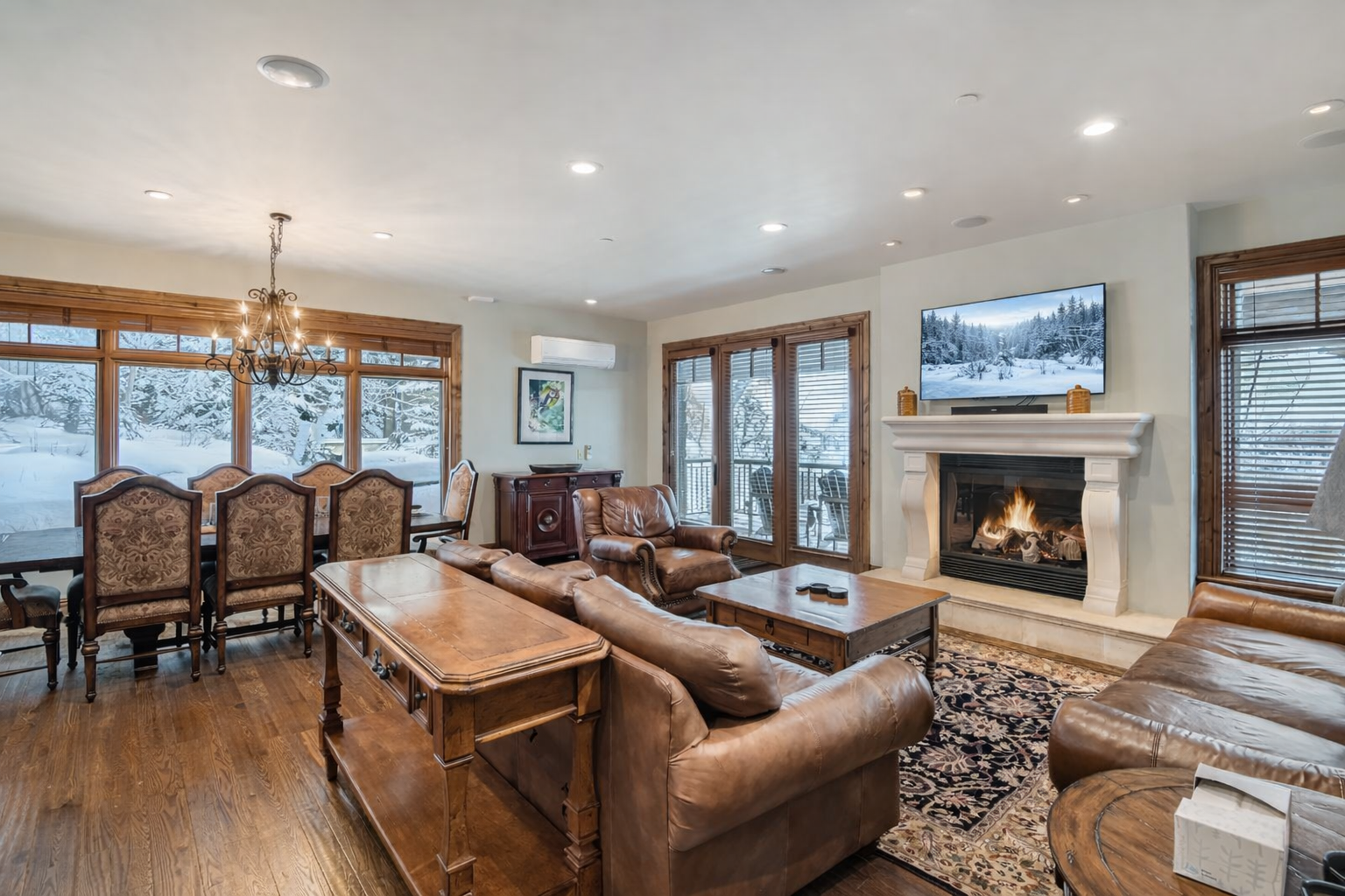 Relax in this bright, open-concept living area at Strand Haus, featuring plush leather seating, a cozy gas fireplace, and a large smart TV.