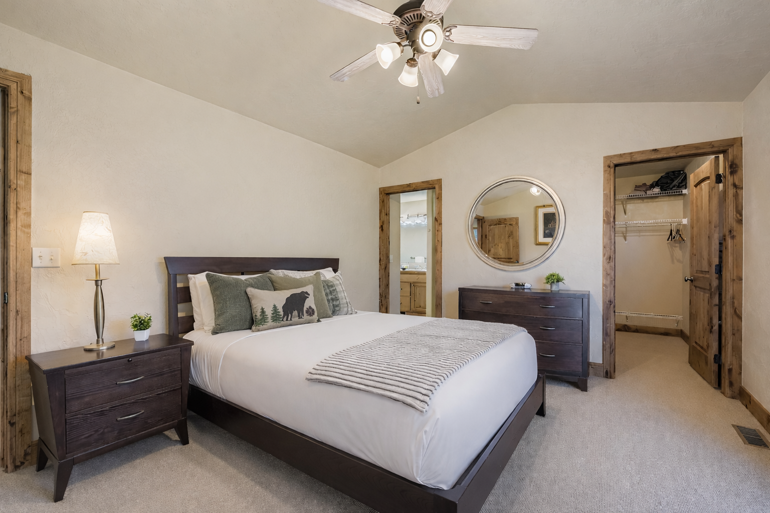 Relax in this bright, modern bedroom featuring a queen bed, vaulted ceilings, and sleek dark-wood furniture. A serene mountain retreat perfectly situated for your next Park City adventure.