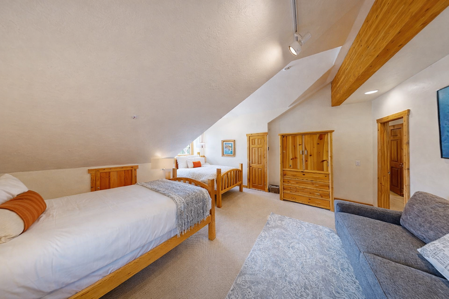 Relax in your cozy twin bedroom with warm wood accents, exposed beams, and comfortable seating for ultimate mountain lodge comfort.