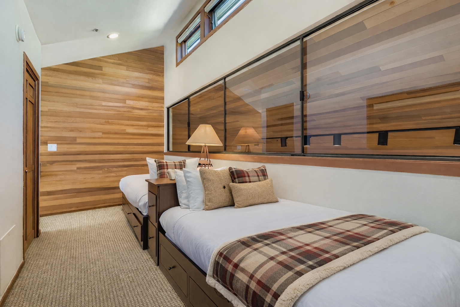 Cozy cabin-style bedroom with warm wood walls and plaid accents creates your perfect mountain retreat sanctuary.