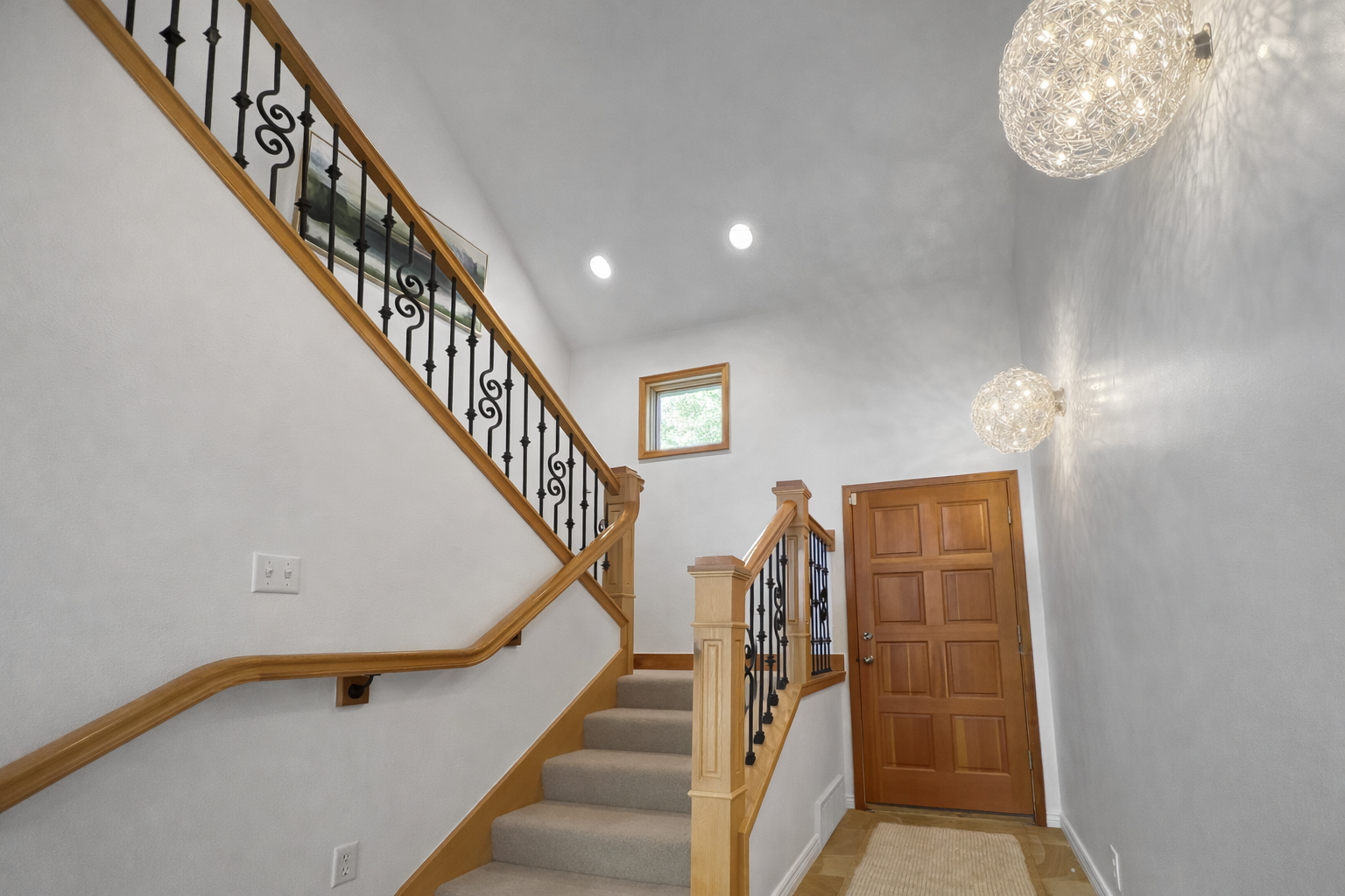 Step into this elegant home featuring a grand entry and a sweeping hardwood staircase with intricate iron balusters, leading up to the rest of the house.