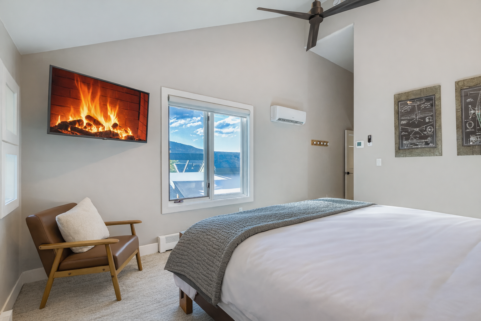 Retreat to the primary suite with a plush king bed, vaulted ceilings, and large windows offering scenic views.