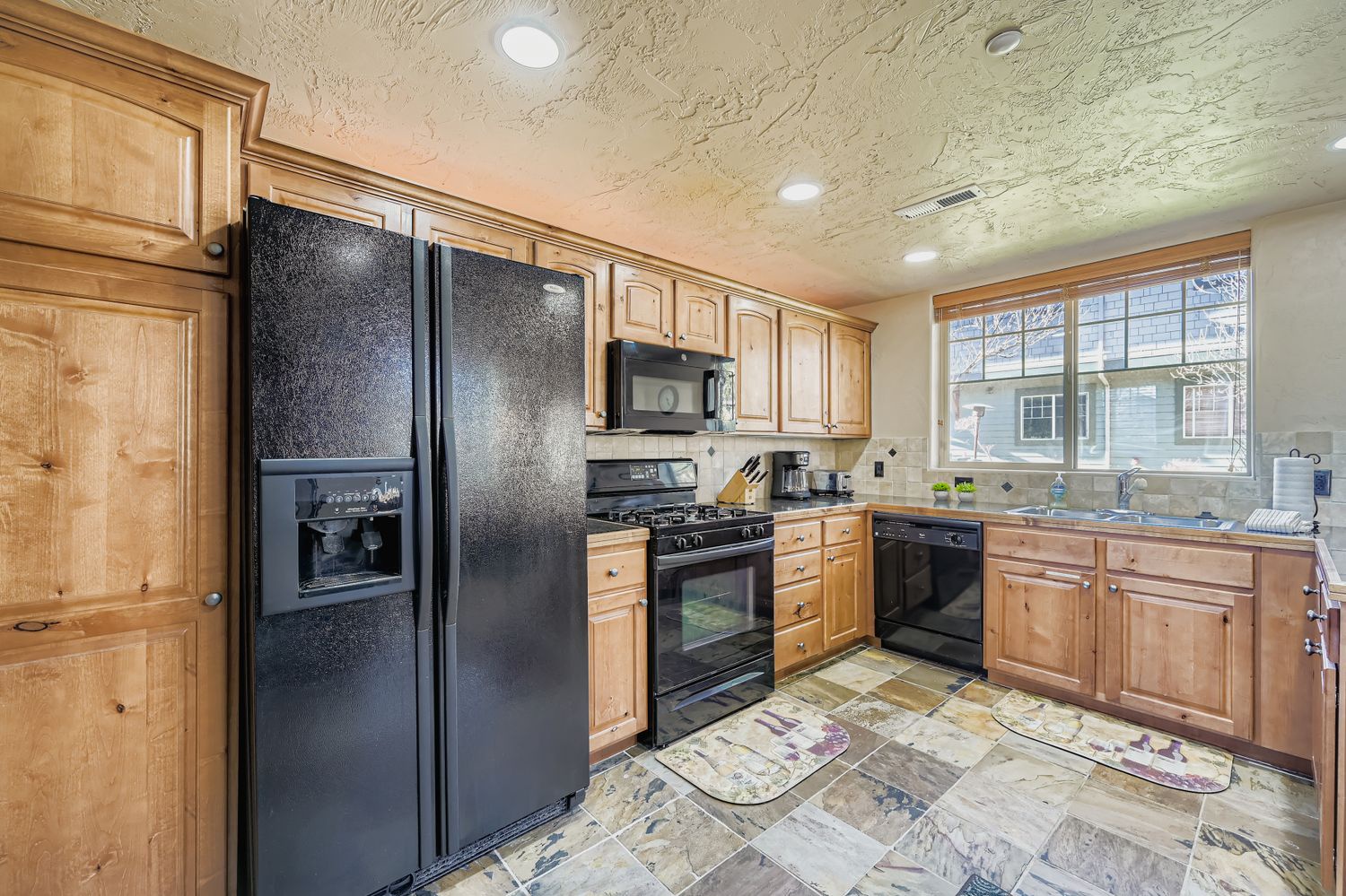 Your fully equipped kitchen features warm wood cabinets, modern black appliances, and spacious countertops perfect for preparing meals during your stay.