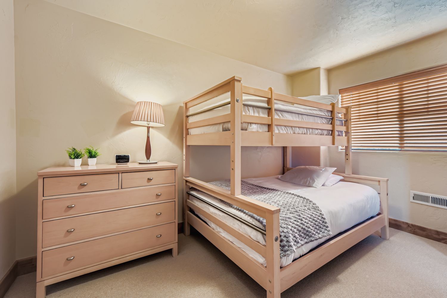 Your cozy bedroom features a practical bunk bed setup with quality bedding and ample dresser storage, perfect for families or groups sharing space comfortably.